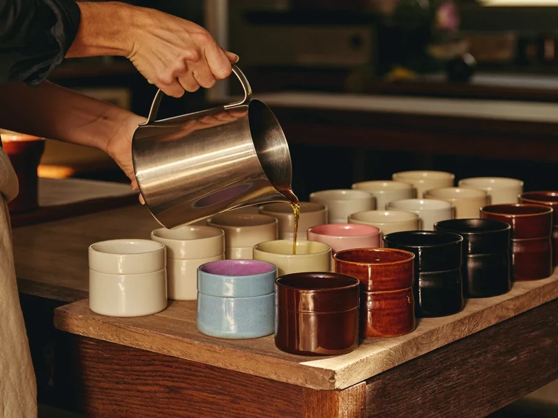 Versement de cire fondue dans des rangées de pots en céramique